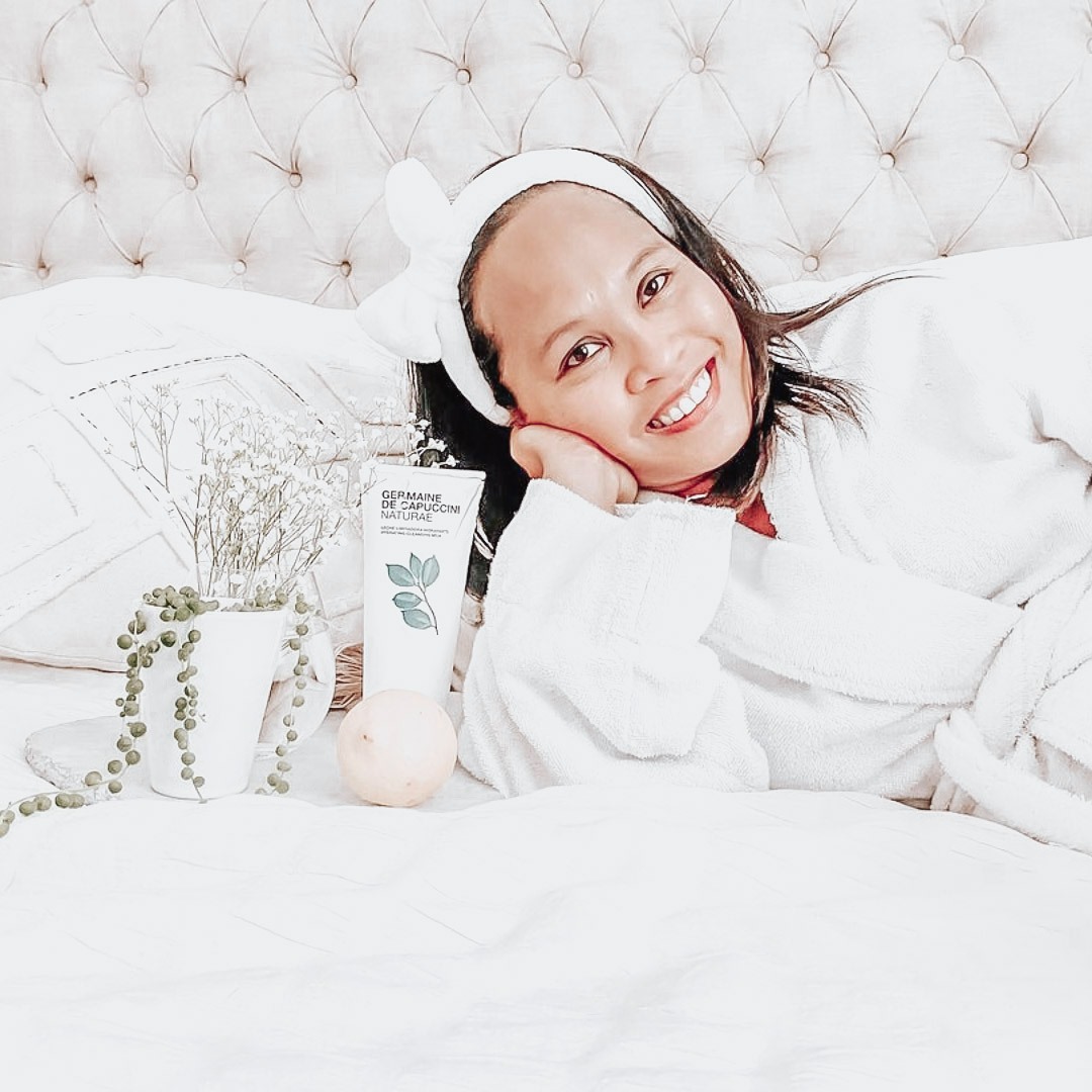 beauty influencer showing her favorite face cleanser from germaine de cappuccino on her bed