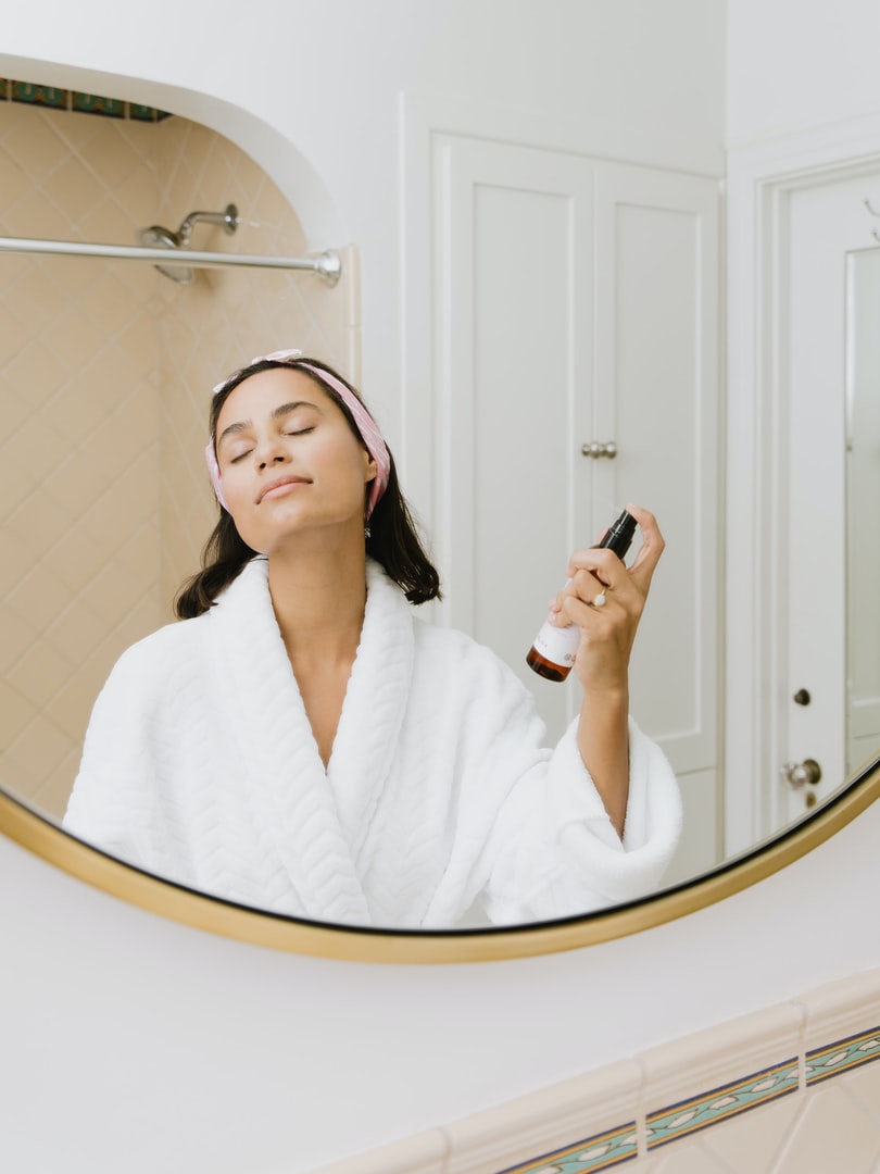 women spraying a facial toner on her face